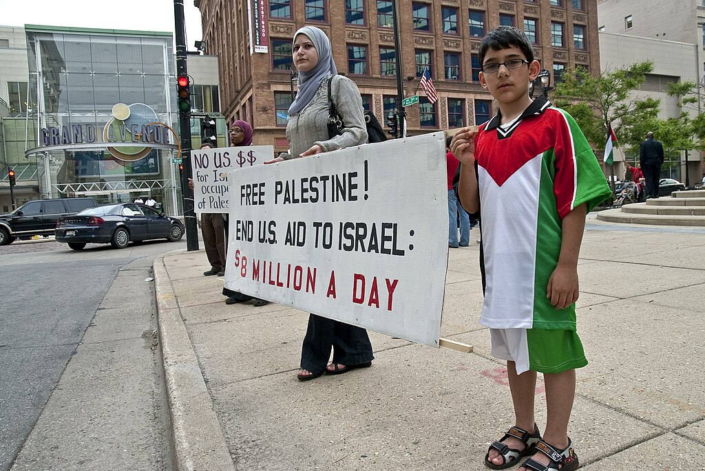 Mother and son reading a sign advocating to free Palestine at a rally
